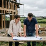 Couple de futurs propriétaires consultant des plans devant leur maison en construction en Ille-et-Vilaine